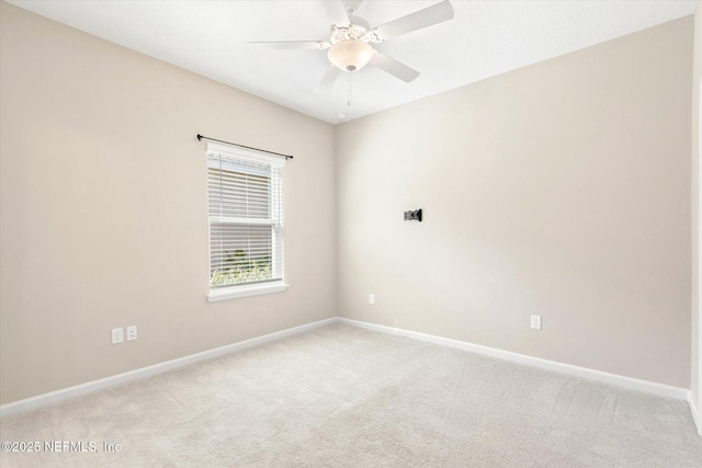 spare room featuring baseboards, light carpet, and a ceiling fan