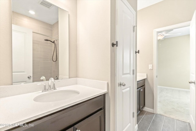 full bath featuring vanity, baseboards, visible vents, tiled shower, and ceiling fan