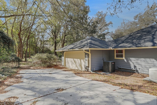 view of home's exterior with central AC unit and driveway