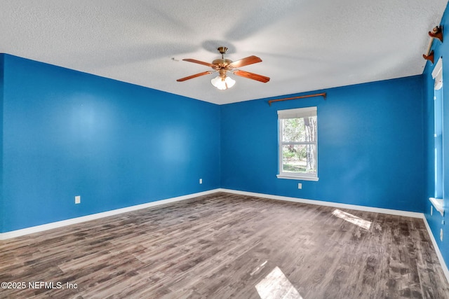 empty room with a textured ceiling, baseboards, ceiling fan, and wood finished floors