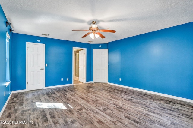 unfurnished bedroom featuring a ceiling fan, visible vents, wood finished floors, baseboards, and a textured ceiling