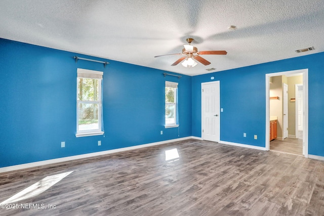 unfurnished bedroom featuring visible vents, baseboards, a textured ceiling, and wood finished floors