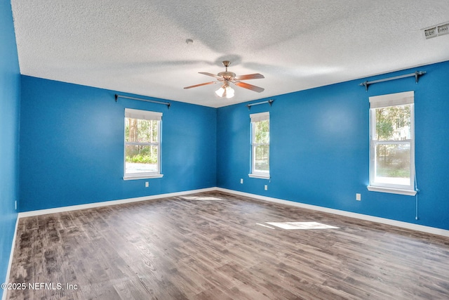 empty room with visible vents, baseboards, ceiling fan, wood finished floors, and a textured ceiling