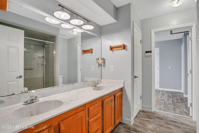 full bath with a textured ceiling, wood finished floors, a stall shower, and a sink