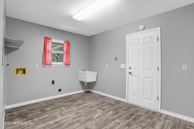 laundry room featuring washer hookup, a textured ceiling, wood finished floors, baseboards, and laundry area