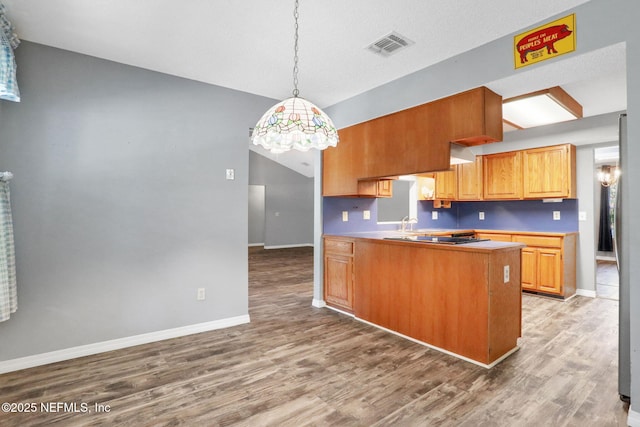 kitchen with visible vents, a peninsula, baseboards, and wood finished floors