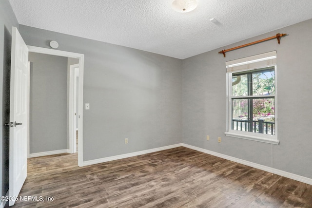 empty room with baseboards, a textured ceiling, and wood finished floors