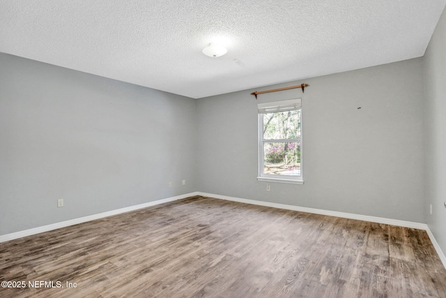 spare room featuring wood finished floors, baseboards, and a textured ceiling