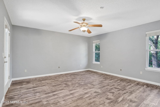 spare room featuring baseboards, wood finished floors, a textured ceiling, and ceiling fan