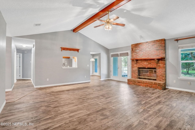 unfurnished living room with vaulted ceiling with beams, a textured ceiling, ceiling fan, and wood finished floors