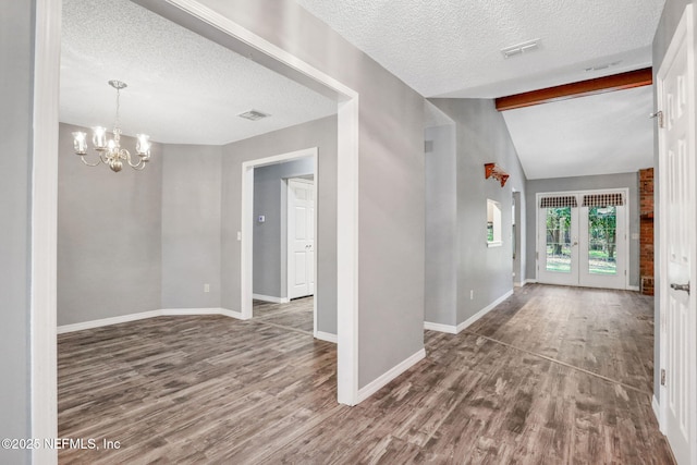 foyer featuring an inviting chandelier, vaulted ceiling with beams, wood finished floors, and visible vents