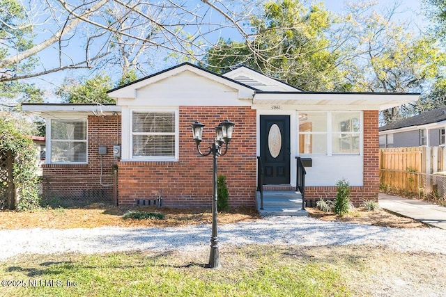 bungalow-style home featuring entry steps, fence, brick siding, and crawl space