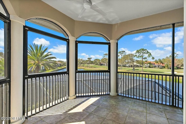 unfurnished sunroom with a ceiling fan and a water view