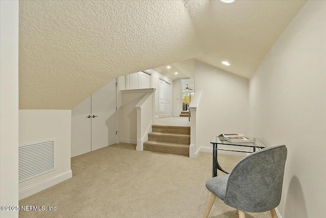 additional living space featuring visible vents, a textured ceiling, recessed lighting, light colored carpet, and vaulted ceiling