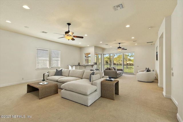 living room with visible vents, carpet flooring, and a ceiling fan