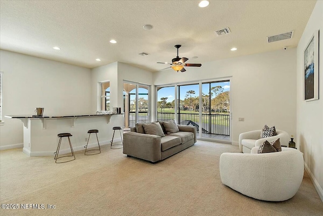 living room featuring recessed lighting, visible vents, and light colored carpet