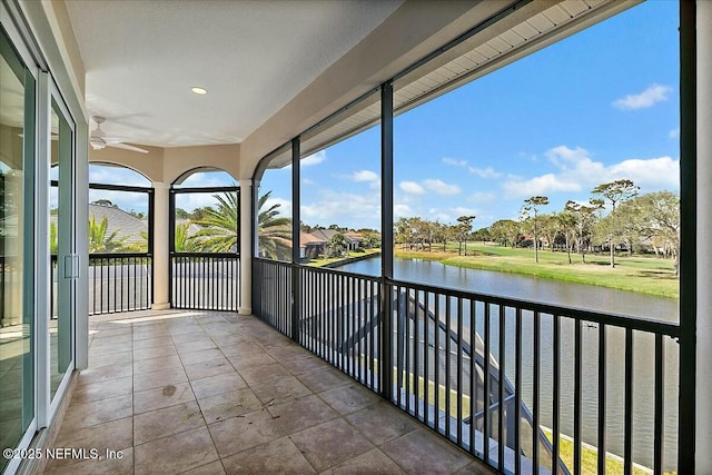 unfurnished sunroom with a ceiling fan and a water view