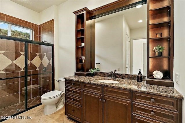 bathroom featuring toilet, a stall shower, vanity, and tile patterned flooring