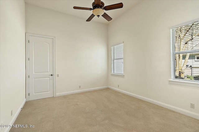 spare room with baseboards, a healthy amount of sunlight, light colored carpet, and ceiling fan