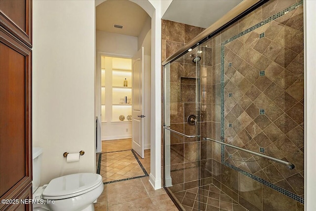 bathroom with tile patterned flooring, toilet, and a stall shower