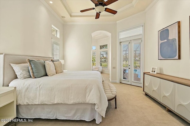 bedroom with light carpet, access to outside, a tray ceiling, arched walkways, and crown molding