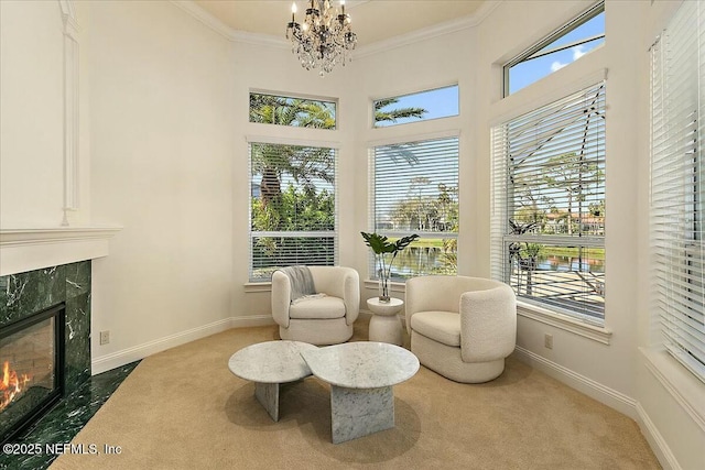 living area with a high end fireplace, carpet floors, crown molding, baseboards, and a chandelier