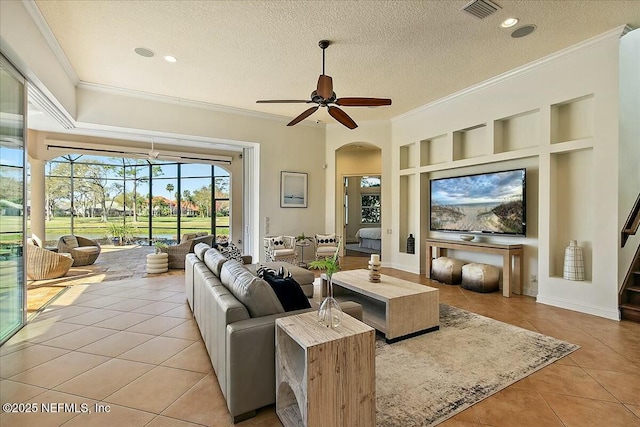 living room featuring visible vents, built in features, ornamental molding, arched walkways, and light tile patterned flooring