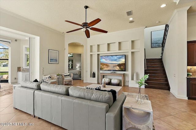 living area featuring light tile patterned floors, arched walkways, a ceiling fan, and crown molding