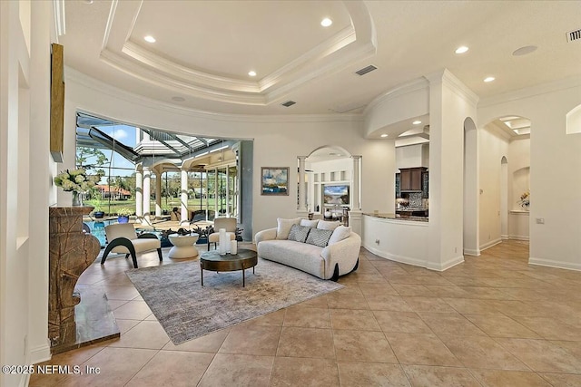 living area with arched walkways, crown molding, a tray ceiling, and light tile patterned flooring