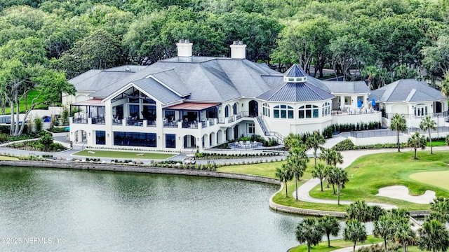 rear view of house featuring a chimney and a water view