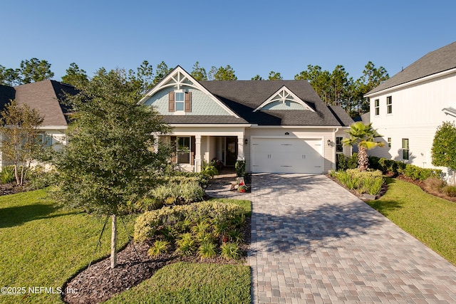 view of front of home with a front lawn, an attached garage, driveway, and a shingled roof