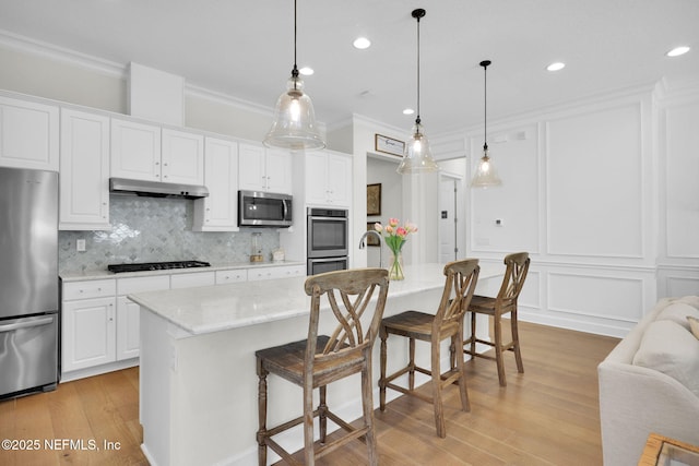 88 Village Grande Dr, Ponte Vedra, FL 32081 - kitchen featuring tasteful backsplash, under cabinet range hood, ornamental molding, appliances with stainless steel finishes, and a decorative wall
