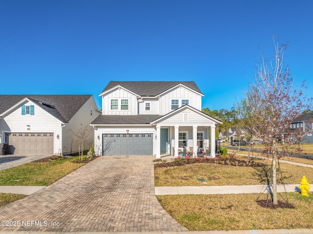 view of front of house with decorative driveway, an attached garage, a front yard, board and batten siding, and a porch