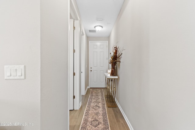 hallway featuring light wood finished floors and baseboards