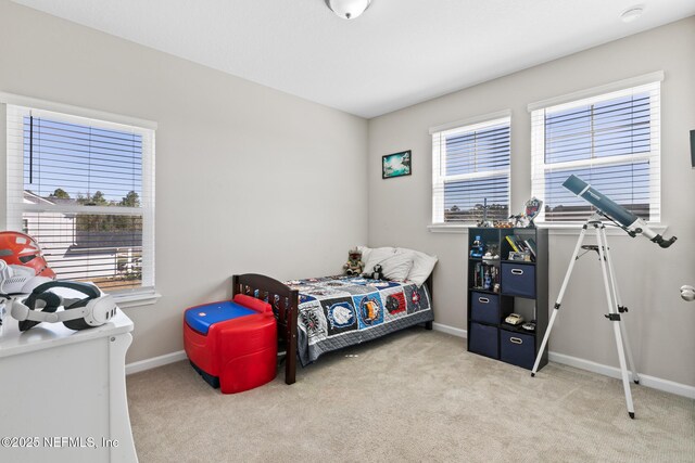 carpeted bedroom featuring baseboards and multiple windows