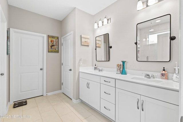 bathroom featuring walk in shower, baseboards, double vanity, a sink, and tile patterned flooring
