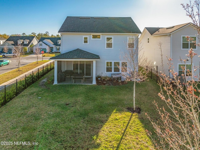 rear view of house with a fenced backyard, a lawn, a shingled roof, and a sunroom