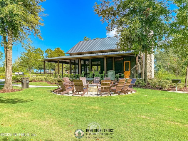 back of house with a lawn, metal roof, an outdoor fire pit, and a patio