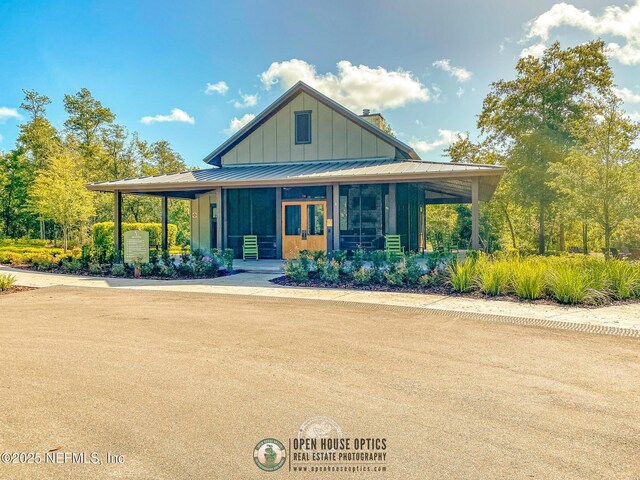 farmhouse inspired home featuring metal roof, a chimney, a standing seam roof, and board and batten siding