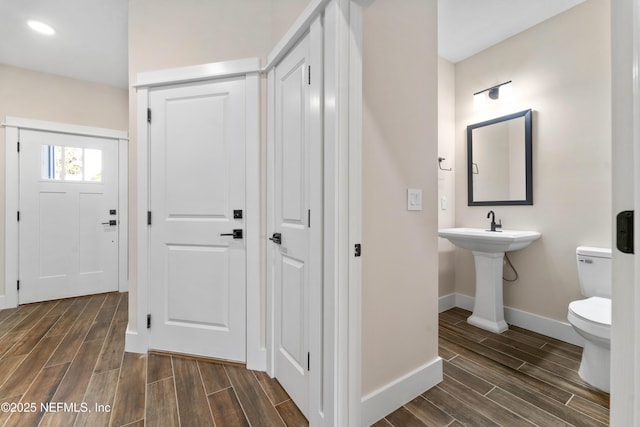 bathroom featuring baseboards, toilet, and wood finish floors