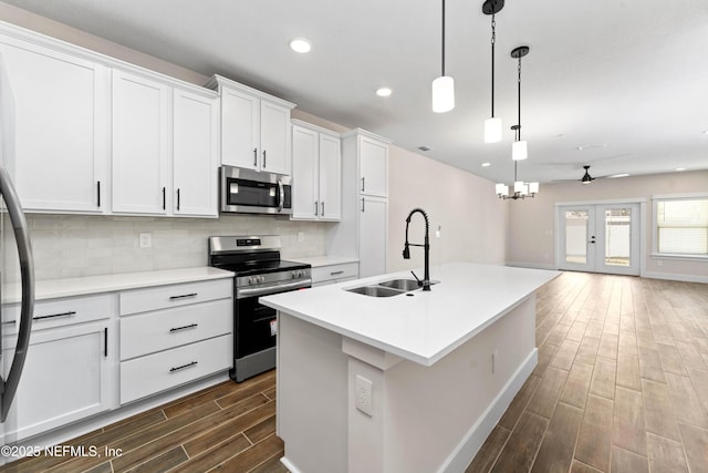 kitchen with wood finish floors, a sink, stainless steel appliances, tasteful backsplash, and open floor plan