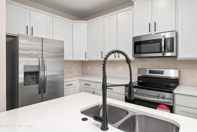 kitchen featuring backsplash, white cabinetry, stainless steel appliances, and light countertops