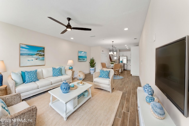 living area featuring recessed lighting, ceiling fan with notable chandelier, and wood finish floors