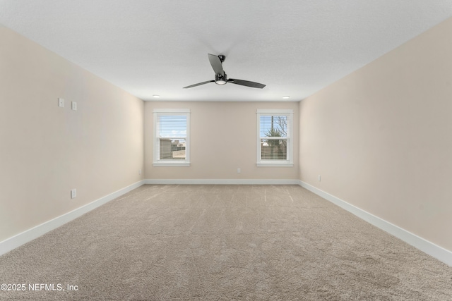 spare room with light colored carpet, baseboards, and ceiling fan