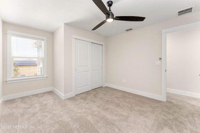 unfurnished bedroom featuring carpet, visible vents, a closet, and baseboards