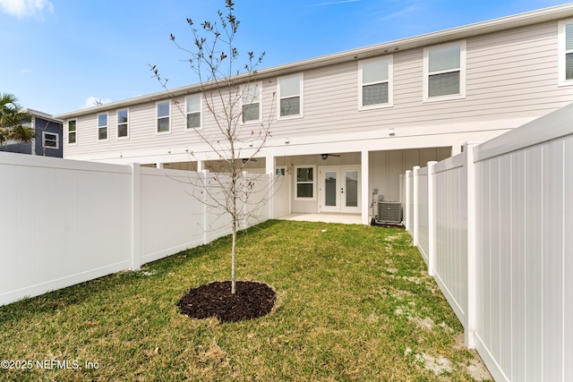 rear view of property featuring central AC, a yard, french doors, and a fenced backyard