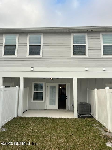 rear view of house featuring a patio, central air condition unit, a yard, and fence