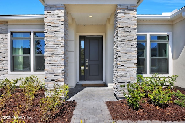 entrance to property featuring stone siding and stucco siding