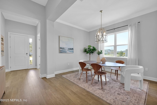 dining space with crown molding, a notable chandelier, wood finished floors, and baseboards