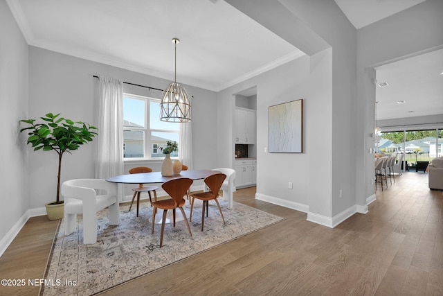 dining room featuring wood finished floors, baseboards, and ornamental molding